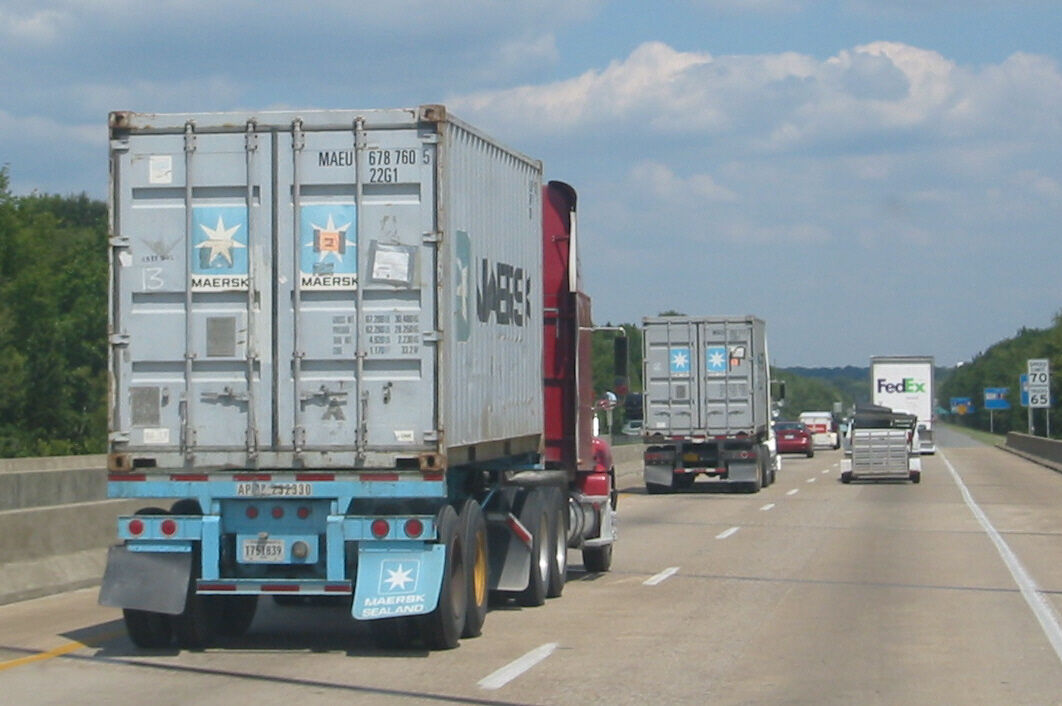 Semi trucks hauling shipping containers on a U.S. interstate highway